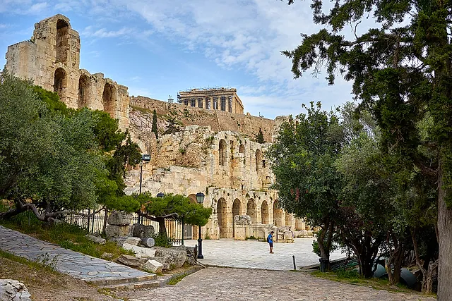The Odeon of Herodes Atticus under the Acropolis, its stone arches rising above the path with the Parthenon on the hill behind
